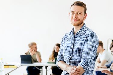 Mann mittleren Alters steht inmitten einer Klasse