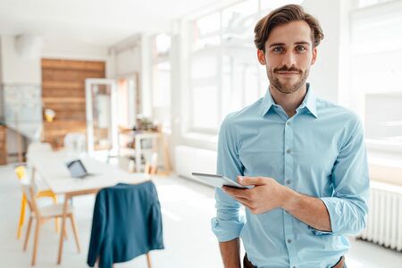 Junger Mann im Businessoutfit mit einem iPad in der Hand