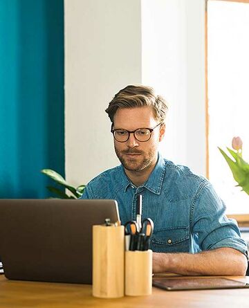 Ein Mann arbeitet von Zuhause aus an seinem Laptop und nutzt so die Flexibilität im Fernstudium