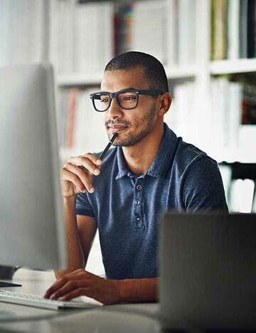 Student sitzt vor seinem Laptop zuhause und lernt für sein Fernstudium