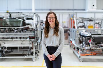 HFH Bachelorstudiengang Wirtschaftsingenieurwesen Eine Frau steht in einer Produktionshalle und lächelt in die Kamera