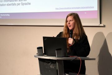 Dozentin Dr. Seibert spricht stehend an Redepult