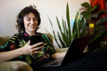 Eine Person mit Laptop und Handy.