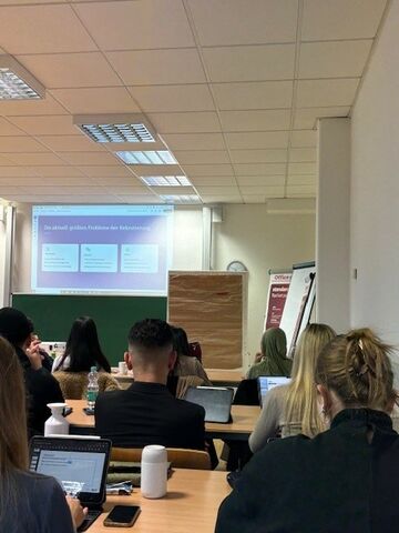 Studierende sitzen an Tischen im Seminar.